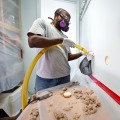 Weatherization technician injecting dense-pack cellulose insulation into home's interior walls.