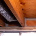 A gray mastic was applied around the edges of a basement rim joist cavity.