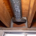 A gray mastic was applied around the edges of a basement rim joist cavity with ductwork between the joist cavity.
