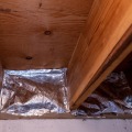 Foil faced insulation is cut to fit between the basement rim joist cavities.
