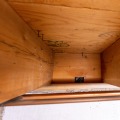 A wood framed basement rim joist cavity with a one by two inch hole in the bottom of the rim joist.