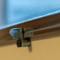 Close up image of a storm window metal fastener attached with a drywall screw.
