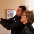 A weatherization energy auditor holding an infrared camera shows a client the camera screen.