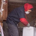 A person in a truck wearing a dust mask cuts open a bag of cellulose insulation from the back of a work truck.