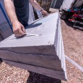 A worker holds multiple layers of rigid foam with a handle made of plastic zip ties.