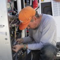 A worker tightens a screw during a furnace installation in a manufactured home. 