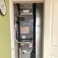 A dark gray heat pump unit installed inside a closet. 