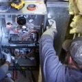 Two technicians are installing a gas furnace in a home.