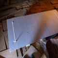An insulated Styrofoam lid is placed over the attic access opening of a partially floored attic.