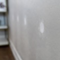 A series of two inch round holes patched with a white one-time spackle looking down the wall of a residential home.